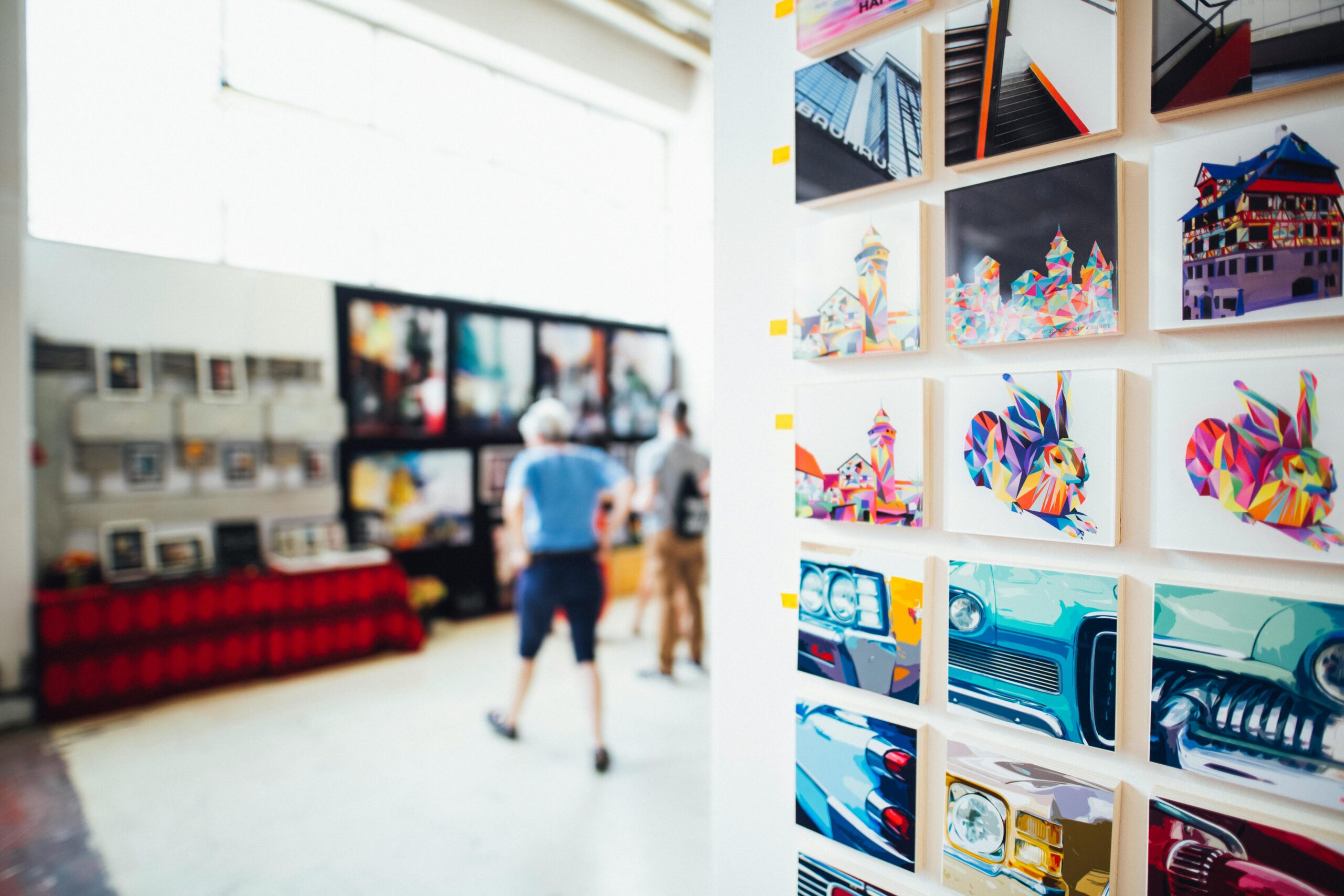 Colorful artwork showcased in a modern gallery setting with people browsing.